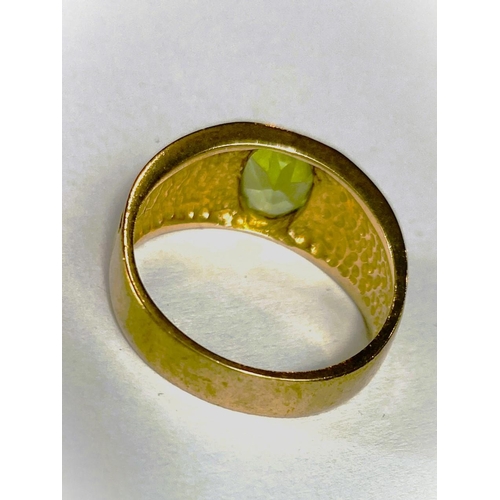 668 - A yellow metal wide ring, stamped 375, with Greek key style decoration, set oval peridot coloured st... 