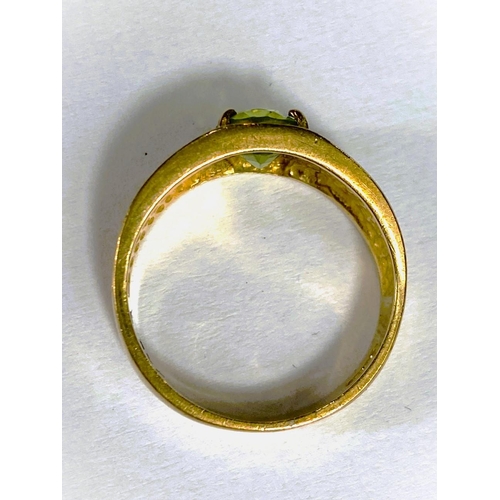 668 - A yellow metal wide ring, stamped 375, with Greek key style decoration, set oval peridot coloured st... 