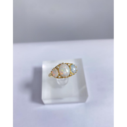 682 - An 18 carat gold dress ring set large central opal flanked by 2 smaller opals and 4 small diamonds