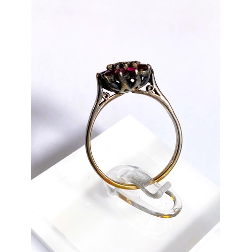 684 - A yellow metal ring stamped 18ct with central illusion set diamond surrounded by rubies, 4.2gm