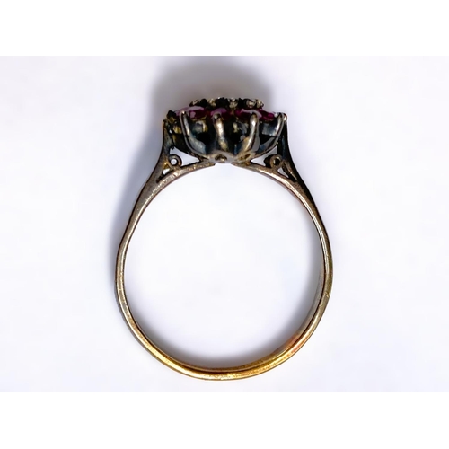 684 - A yellow metal ring stamped 18ct with central illusion set diamond surrounded by rubies, 4.2gm