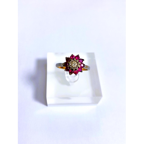 684 - A yellow metal ring stamped 18ct with central illusion set diamond surrounded by rubies, 4.2gm