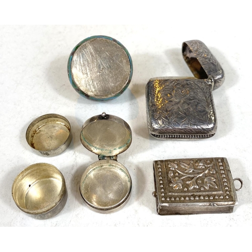 711 - A hallmarked silver vesta case, a white metal vesta in the form of a book and three white metal pill... 