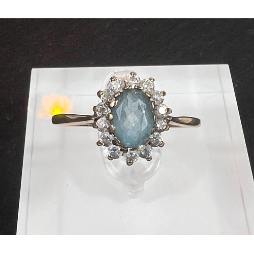 763 - A 9 carat hallmarked gold dress ring set with a central turquoise coloured stone surrounded by clear... 