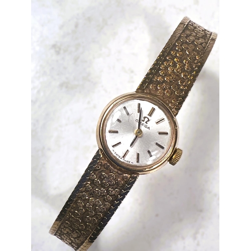 766 - A ladies 9 carat hallmarked gold OMEGA wristwatch with integral hallmarked gold bark effect strap, 1... 