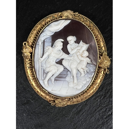 775 - A cameo brooch depicting classical Greek figures in an intricate yellow metal setting, height 9.25 c... 