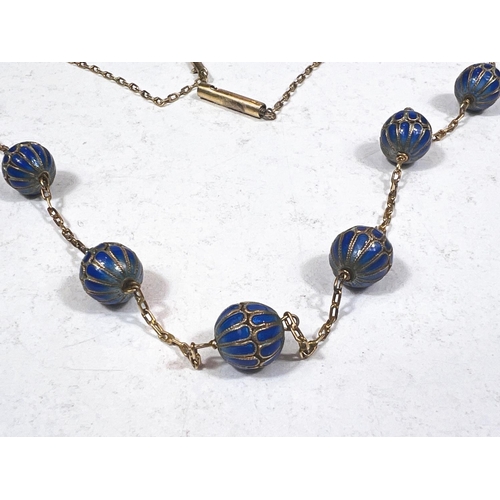 776 - A yellow metal chain necklace with integral 7 blue enamelled beads, length 78cm.