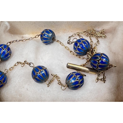 776 - A yellow metal chain necklace with integral 7 blue enamelled beads, length 78cm.