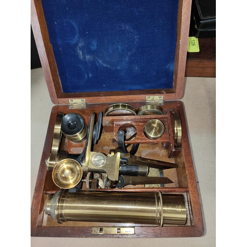 127 - An early 20th century brass tripod microscope in a fitted wooden box, not signed