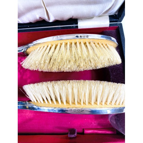 612 - A silver pair of cased hairbrushes and a comb