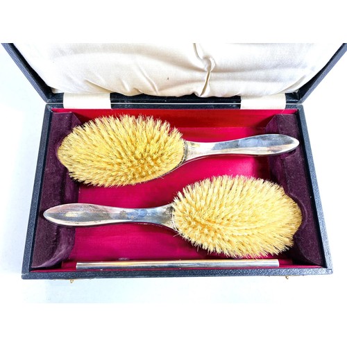 612 - A silver pair of cased hairbrushes and a comb