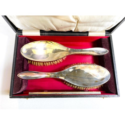 612 - A silver pair of cased hairbrushes and a comb