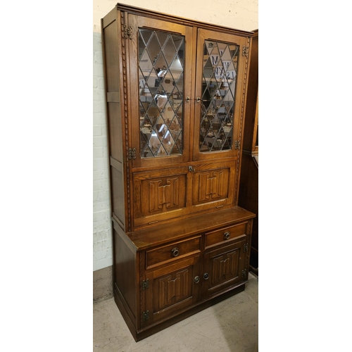 986 - A Jaycee Furniture oak Jacobean style full height display cabinet with leaded glass doors above, fal... 