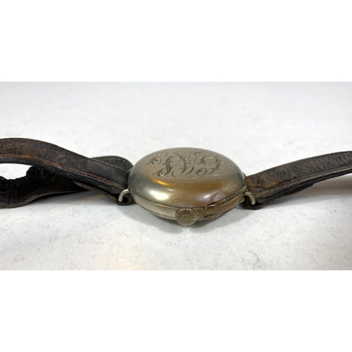 779E - A WWI period officers trench watch with spring protective monogrammed front, on leather strap