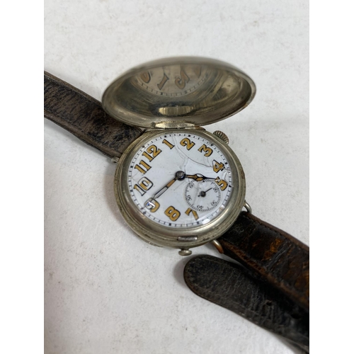 779E - A WWI period officers trench watch with spring protective monogrammed front, on leather strap