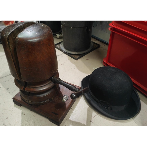 116A - An antique wooden hat stretcher on stand with metal turning handle, and a black bowler hat