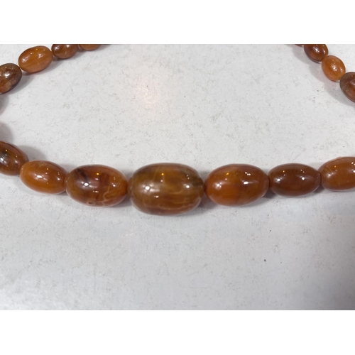 761B - A mottled amber coloured Bakelite necklace with graduating oval beads 