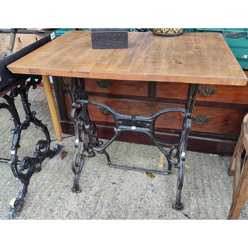 876 - A cast metal based pub table with stained wooden top, 120 x 70cm; a table with cast iron treadle sew... 