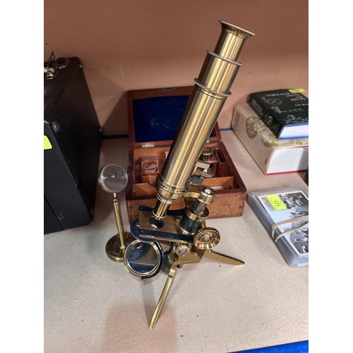 127 - An early 20th century brass tripod microscope in a fitted wooden box, not signed