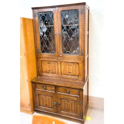 933 - A Jaycee Furniture oak Jacobean style full height display cabinet with leaded glass doors above, fal... 