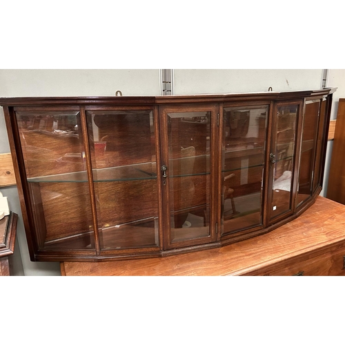 928 - An unusual wall mounted mahogany cabinet with bow front, enclosed by 2 doors with bevelled glass pan... 