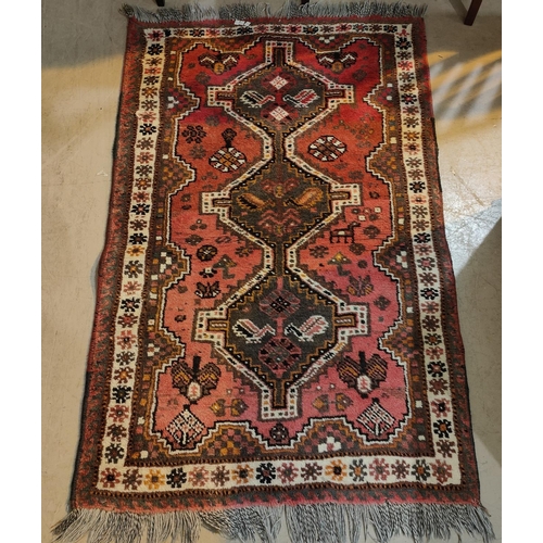 986 - A 20th century hand knotted red ground Persian rug with central barred triple medallions