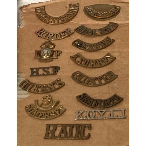 252 - A collection of military shoulder badges on board, a collection of buttons etc and books including f... 