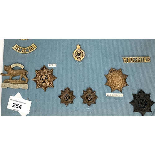 254 - A collection of Military badges on card including various  regiments