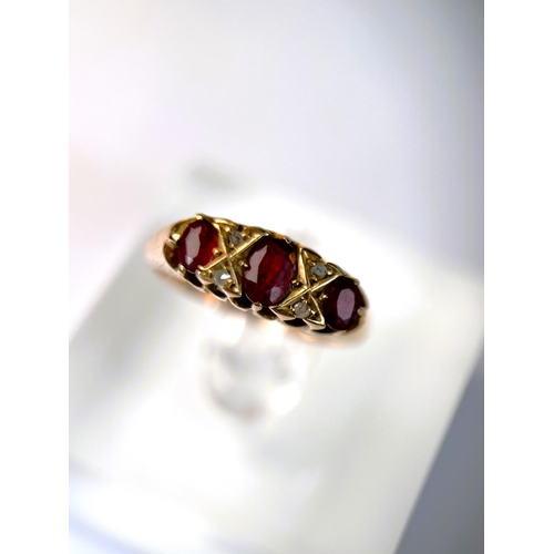 618 - An 18 carat hallmarked gold ring set with 3 garnets and diamond chips, 5.5 gm, size L