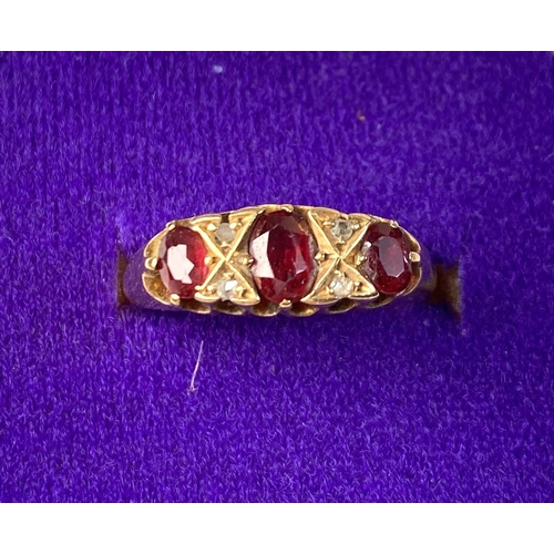 618 - An 18 carat hallmarked gold ring set with 3 garnets and diamond chips, 5.5 gm, size L