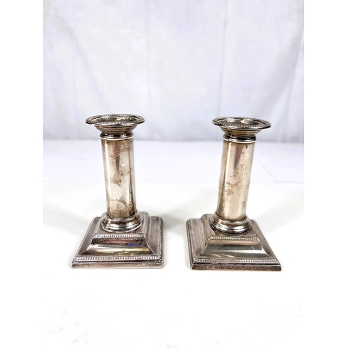 775 - A pair of hallmarked silver dwarf candlesticks with beaded borders on square weighted bases, ht. 13c... 