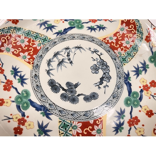 401A - An Imari shallow dish decorated in polychrome with flowers and branches, signature to base, dia. 30c... 