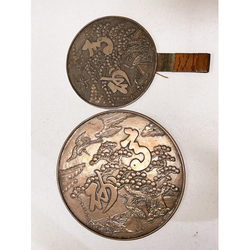 405 - Two Chinese bronze mirrors, one highly polished side, the other embossed, one with handle