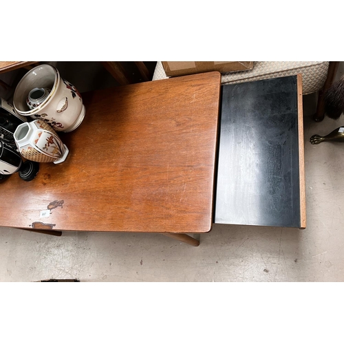 957 - A 1960's rectangular teak coffee table with leaves to each end; a similar table