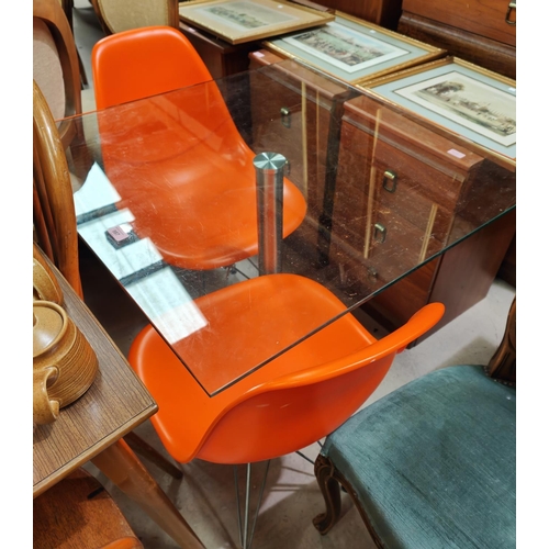 987 - A square glass kitchen table with brushed steel pedestal, two bright orange dining chairs 