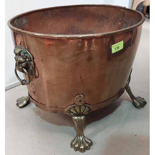 136 - An oval copper log box with brass lion mark handles and and paw feet.