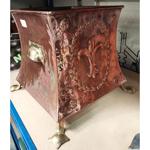 17 - An Arts and Crafts embossed copper coal bin of square waisted form with brass mounts and feet.