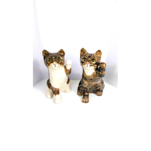 561 - Two Winstanley cats, glass eyes, both seated with one paw raised,  signed, size 3 (each a.f)