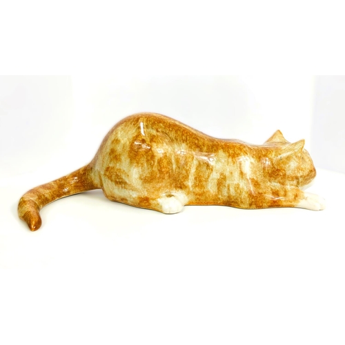 567 - A Winstanley cat, glass eyes, lying down, length 26cm, signed; another similar with glass eyes, sign... 