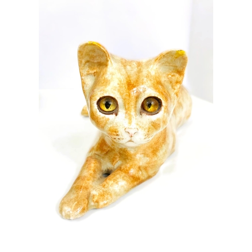 567 - A Winstanley cat, glass eyes, lying down, length 26cm, signed; another similar with glass eyes, sign... 