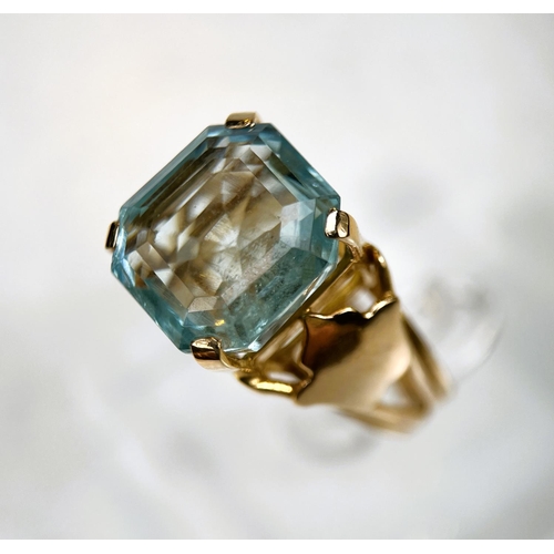 684 - A 1970's yellow metal dress ring with a large square cushion cut aquamarine colour stone in raised s... 