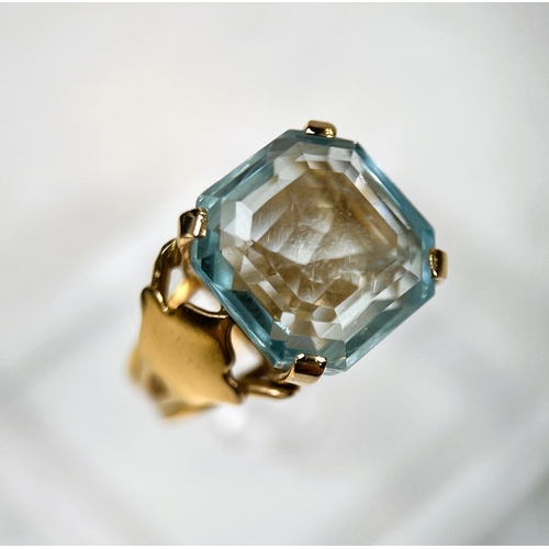 684 - A 1970's yellow metal dress ring with a large square cushion cut aquamarine colour stone in raised s... 