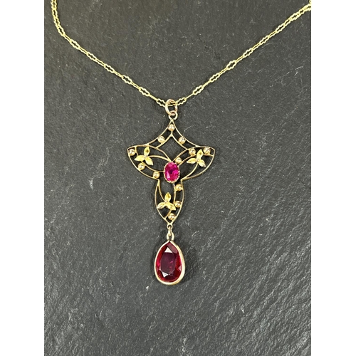 685 - An Art Nouveau style yellow metal pendant stamped 9ct, with central ruby and ruby colour drop, on fi... 