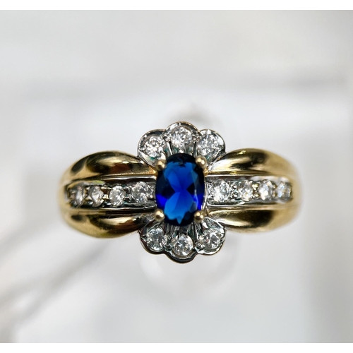 723 - A 9 carat hallmarked gold dress ring set with a blue stone, surrounded by clear stones, 3.4gm, size ... 