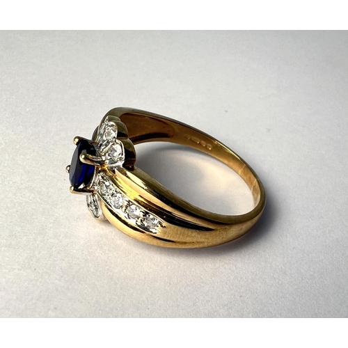 723 - A 9 carat hallmarked gold dress ring set with a blue stone, surrounded by clear stones, 3.4gm, size ... 