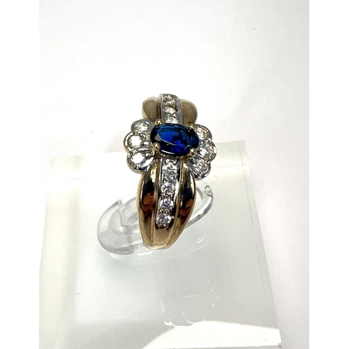 723 - A 9 carat hallmarked gold dress ring set with a blue stone, surrounded by clear stones, 3.4gm, size ... 