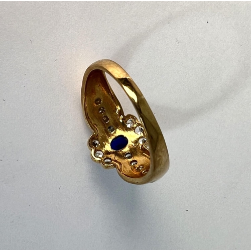 723 - A 9 carat hallmarked gold dress ring set with a blue stone, surrounded by clear stones, 3.4gm, size ... 