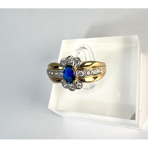 723 - A 9 carat hallmarked gold dress ring set with a blue stone, surrounded by clear stones, 3.4gm, size ... 