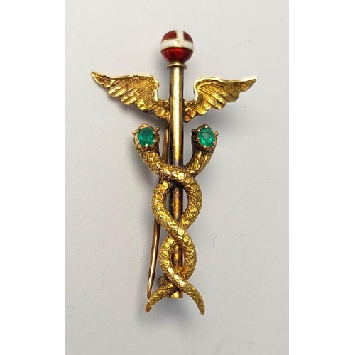 786 - A yellow metal Caduceus brooch set 2 emeralds, enamelled finial, (tests 14ct) base metal pin. 3.74gm... 