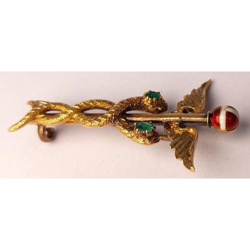 786 - A yellow metal Caduceus brooch set 2 emeralds, enamelled finial, (tests 14ct) base metal pin. 3.74gm... 